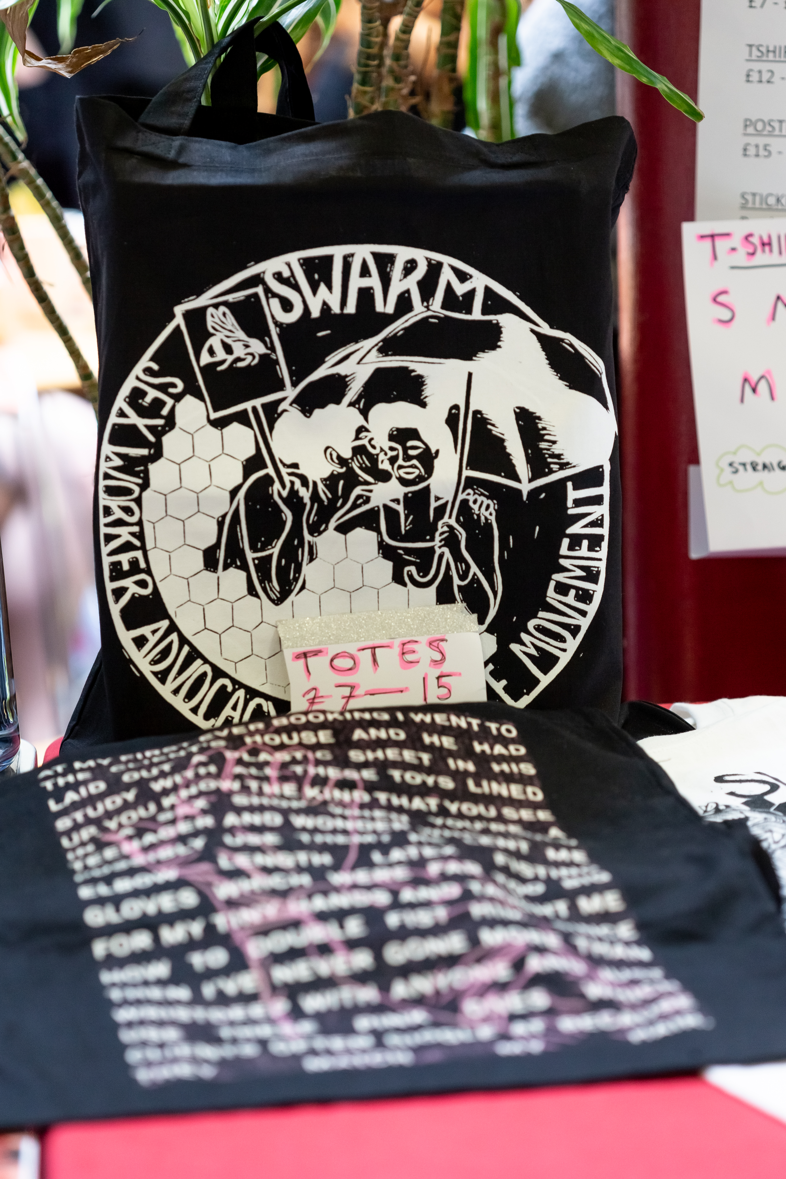A table featuring a black SWARM tote bag for sale.